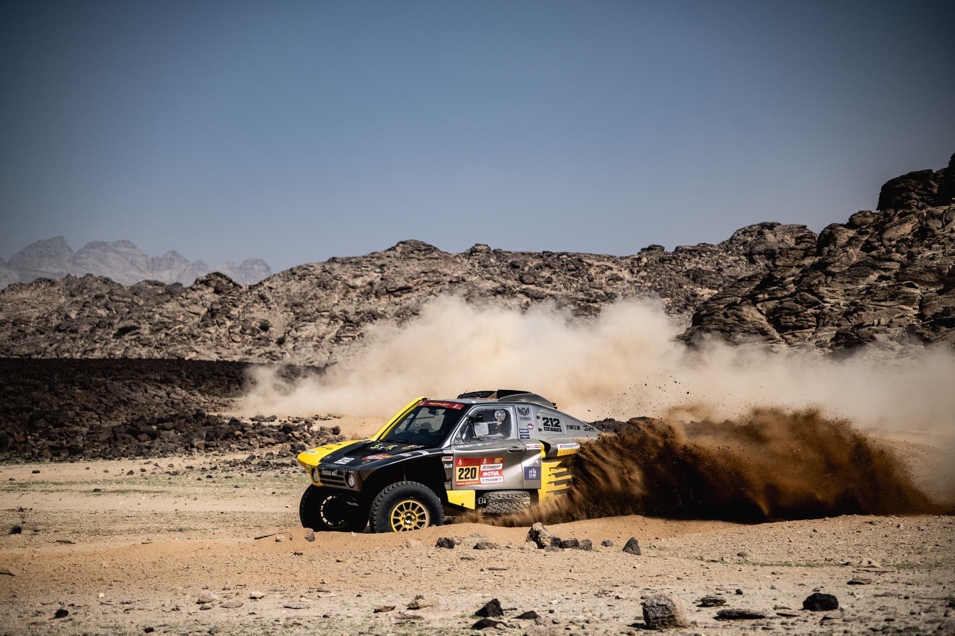 HWM T1+ race car number 220 throwing a rooster tail of dust on a desert track